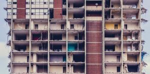 Facciata di un edificio in demolizione con piani e stanze a vista, simbolo di abusi edilizi e procedure esecutive