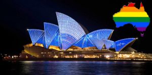 L'Opera House di Sydney illuminata di blu di notte, con la mappa dell'Australia colorata con la bandiera arcobaleno, simbolo di una nazione multietnica e inclusiva