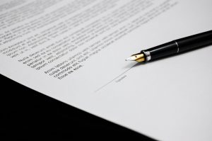 Una penna stilografica su un documento legale, pronta per la firma, simboleggia il patrocinio a spese dello stato e la liquidazione del compenso