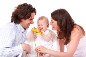 Una famiglia felice, con padre, madre e un bambino che gioca con un fiore giallo, simboleggia il diritto di famiglia