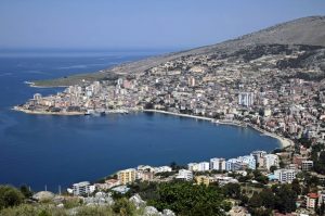 Vista aerea di Saranda, Albania, con la città che si estende lungo la costa e un'ampia baia blu, simbolo di opportunità per il turismo e gli investimenti