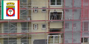 Bandiera della Regione Puglia e un edificio in ristrutturazione con ponteggi, simboleggiando le opportunità in edilizia