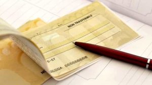 Un assegno bancario aperto con la dicitura NON TRASFERIBILE e una penna rossa, simbolo di transazioni e obblighi legali nel diritto civile e di famiglia
