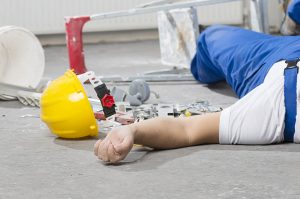 Un lavoratore infortunato a terra con l'elmetto giallo caduto, simboleggiando i rischi della sicurezza sul lavoro e la responsabilità del committente
