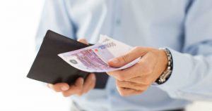 Un uomo estrae banconote da 500 euro da un portafoglio, simboleggiando le spese straordinarie nel diritto di famiglia