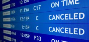 Un tabellone digitale blu mostra voli aerei CANCELED (cancellati), evidenziando il diritto al rimborso