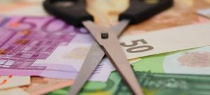 Forbici aperte su banconote euro, simboleggiando il saldo e stralcio e la gestione del debito