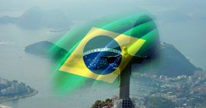 Vista aerea di Rio de Janeiro con il Cristo Redentore e la bandiera brasiliana sovrapposta, simbolo di opportunità per investire in Brasile