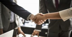 Due professionisti si stringono la mano, simboleggiando accordo e collaborazione nella mediazione civile e commerciale