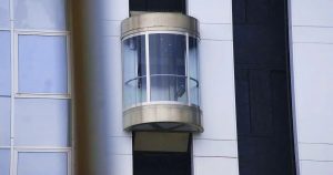 Ascensore esterno moderno con pareti in vetro su un edificio, simbolo di accessibilità e innovazione legale