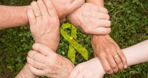 Mani di persone di età diverse si uniscono in un cerchio, simboleggiando il supporto familiare contro il cancro