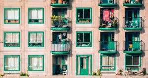 Facciata di un edificio moderno con finestre e balconi, alcuni con piante e arredi, che richiama il Bonus Facciate per la riqualificazione edilizia