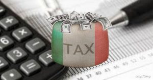 Un sacco di denaro con la bandiera italiana e la scritta TAX su una calcolatrice, simboleggiando le tasse e i versamenti nel diritto tributario