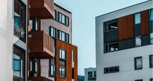 Due moderni edifici con facciate chiare e balconi in legno, riflettendo il tema del diritto immobiliare e della manutenzione