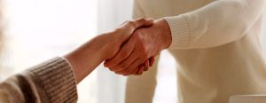 Due persone si stringono la mano, simboleggiando fiducia e riservatezza professionale nella consulenza legale